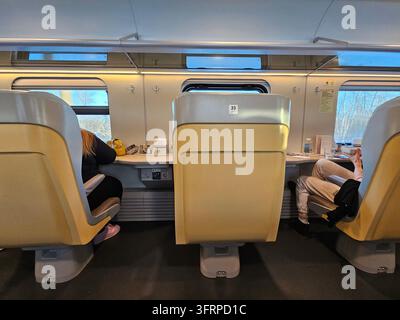 Voie de train avec deux sièges et une table. Une personne est assise sur le siège du milieu. Une autre personne est assise à l'arrière du train dans le restaurant Banque D'Images