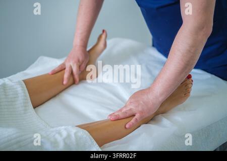 Dans un salon de beauté, ce service professionnel propose un massage des jambes, un massothérapeute, une femme, un massage du mollet, un massage thérapeutique et des mains duri Banque D'Images