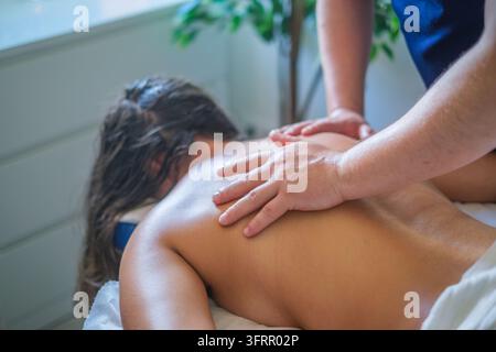 Service de salon de massage professionnel mettant en vedette un massage du dos, un massothérapeute, un massage thérapeutique, une cliente féminine, une femme et le massage pendant un Banque D'Images