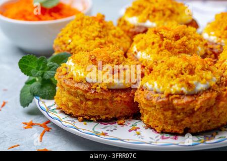 Petits gâteaux maison aux carottes avec crème au fromage frais et décoration de miettes et de carottes râpées sur une assiette, gros plan, mise au point sélective Banque D'Images
