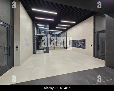 Moscou - 4 juin 2025 : Grand espace ouvert avec une porte vitrée et un panneau indiquant « Sortie ». Il y a une porte métallique noire sur le côté droit de l'entrée de la pièce dans le complexe résidentiel Banque D'Images