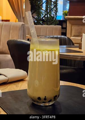 Verre de bubble tea vert avec une paille dedans. Le verre est posé sur une table Banque D'Images