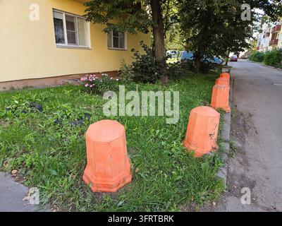 Une rangée de cônes de signalisation orange se trouve dans une zone herbeuse à côté d'un bâtiment. Les cônes sont placés en ligne, avec un à gauche, un au milieu et un à droite. La scène est paisible et calme Banque D'Images