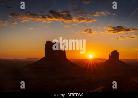 Une photographie de paysage horizontale époustouflante mettant l'accent sur un lever de soleil éclatant dans le Monument Valley Navajo Tribal Park. Le soleil brillant se lève au-dessus du Banque D'Images