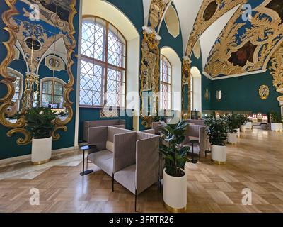 MOSCOU - 15 JAN 2026 : Grande salle avec plafonds ornés et murs bleu-vert. De grandes fenêtres en arc laissent entrer une lumière naturelle douce. Des sièges modernes et des plantes en pot ajoutent du confort. Le sol en bois complète Banque D'Images