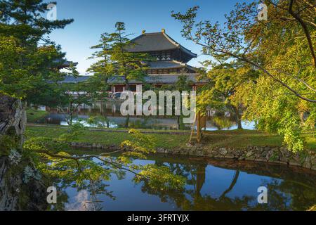 Nara, Japon - 26 sep 2024, Vue panoramique sur l’étang et les arbres vers la façade du temple de Todaiji, Grande salle du Bouddha, avec un ciel bleu nuageux, Nara, Japon Banque D'Images