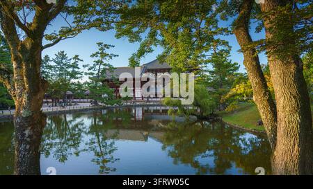 Nara, Japon - 26 sep 2024, Vue panoramique sur l’étang et les arbres vers la façade du temple de Todaiji, Grande salle du Bouddha, avec un ciel bleu nuageux, Nara, Japon Banque D'Images