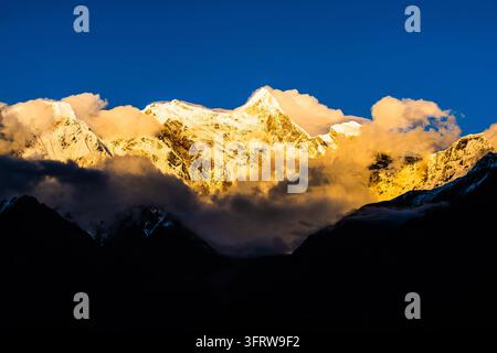 Une lumière dorée éclaire Namjagbarwa (Namcha Barwa) et les sommets enneigés environnants, Nyingchi, Tibet, Chine. Banque D'Images