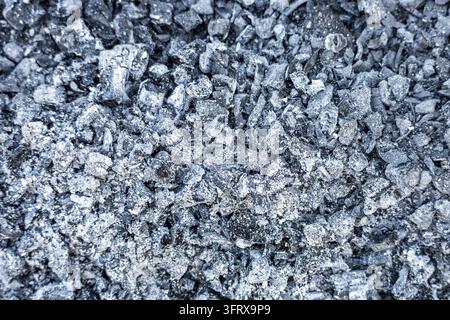 Une vue macro en plein format met en évidence une couche détaillée de cendres de bois grises mélangées à des particules de charbon sombre et à des braises brûlées. La texture poudreuse crée un Banque D'Images