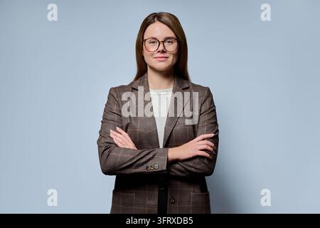 Femme d'affaires confiante portant des lunettes, debout les bras croisés dans un studio Banque D'Images