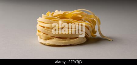 Nids de pâtes tagliatelle crues sur un fond de pierre grise Banque D'Images