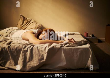 Femme épuisée allongée face contre le matelas représentant un épuisement mental Banque D'Images