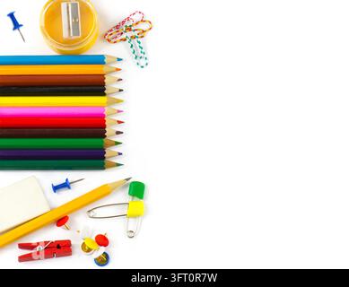 Crayons colorés disposés, taille-crayon, gomme, trombones, punaises, épingles de sûreté et pince à linge formant une bordure lumineuse d fournitures scolaires et de bureau Banque D'Images
