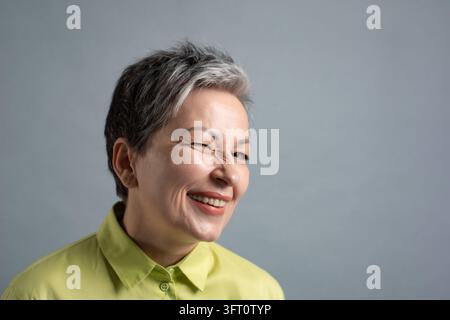 Femme mûre espiègle souriant et riant à l'objectif dans un cliché en studio lumineux Banque D'Images