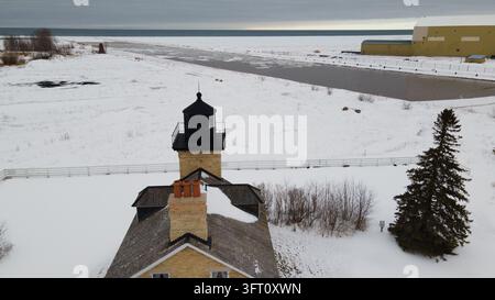 Vue aérienne du phare d'Ontonagon entouré d'un sol enneigé et d'une rive gelée du lac Supérieur à Ontonagon, Michigan, États-Unis. Banque D'Images