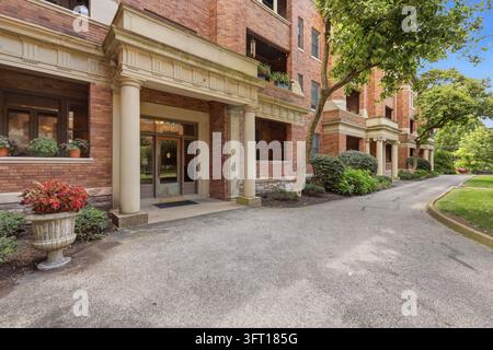 Vue de l'entrée d'un immeuble d'appartements historique en briques avec des colonnes en pierre, des plantes en pot et une allée pavée à Cincinnati, OH, États-Unis. Banque D'Images