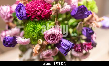 Bouquet de fleurs coloré avec lisianthus violet, une rose rose, chrysanthème magenta et boules de dianthus vert, pris d'en haut avec un fond flou doux Banque D'Images