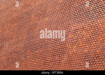 Vue en plein cadre d'un mur de briques rouges, des briques en terre cuite orange et terre cuite disposées en motif de liaison avec des joints de mortier gris. La caméra est inclinée de sorte que Banque D'Images