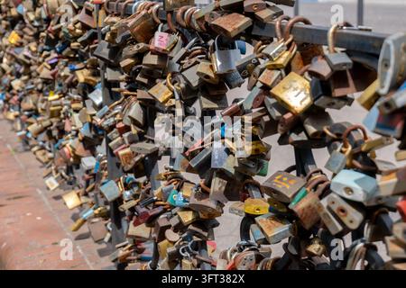 Des centaines de cadenas d'amour sont accrochés densément à la balustrade d'une clôture métallique le long d'une allée, formant une masse colorée de cadenas en laiton, en acier et peints Banque D'Images