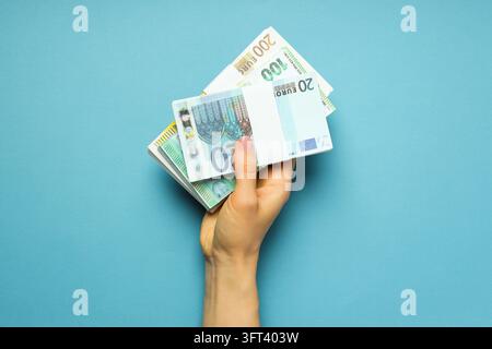 Concept de finances, main féminine tenant de l'argent sur fond bleu Banque D'Images