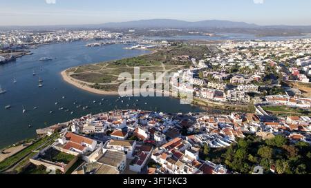 Vue aérienne de la ville côtière de Ferragudo, présentant des maisons traditionnelles blanchies à la chaux, un estuaire de rivière pittoresque, de petites barques de pêche et l'entourage Banque D'Images
