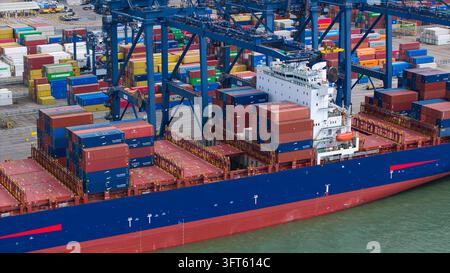 Vue aérienne du port de Felixstowe avec un navire de conteneurs en cours de chargement par des grues, entouré de conteneurs empilés à Felixstowe, en Angleterre Banque D'Images