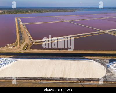 Vue aérienne des étangs d'évaporation de sel aux teintes roses et des grands monticules de sel blancs dans l'usine de sel marin d'Aigues-Mortes, Occitanie, France. Banque D'Images