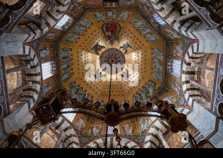 DOME EN MOSAÏQUE OR INTRICATE ET LUMIÈRE PENDANTE, CATHÉDRALE D'ACHAEN, ACHAEN, ALLEMAGNE : Un regard direct vers le haut de la mosaïque dorée étonnamment détaillée sur le plafond de la coupole octogonale d'une chapelle historique, avec un lustre massif et complexe suspendu au centre. INFO : La cathédrale d'Aix-la-Chapelle, premier site du patrimoine mondial de l'UNESCO en Allemagne, est un chef-d'œuvre architectural carolingien fondé par Charlemagne. Combinant des éléments byzantins et gothiques, ce monument historique a servi de lieu de couronnement pour trente et un monarques allemands. Banque D'Images