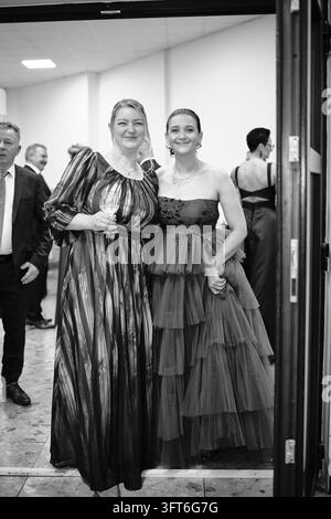 Photographie en noir et blanc de deux femmes en longues robes de soirée posant ensemble dans un encadrement de porte lors d'un bal. Banque D'Images