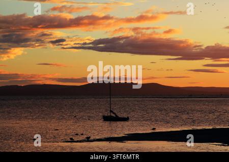Ciel orange, nuages dramatiques et un bateau solitaire sur le lac. Balaton, Hongrie Banque D'Images