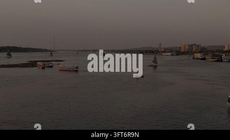 Observation du coucher de soleil sur le Nil à Assouan en Égypte. Plusieurs voiliers croisent la rivière en transportant des touristes et des habitants Banque D'Images