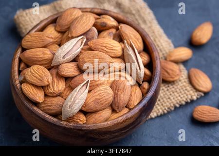 Amandes dans un bol en bois brun sur un fond de table en bois ancien Banque D'Images