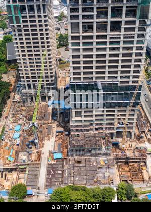 Vue aérienne d'un grand chantier de construction présentant deux gratte-ciel imposants en développement avec plusieurs grues, des armatures d'acier exposées et c Banque D'Images
