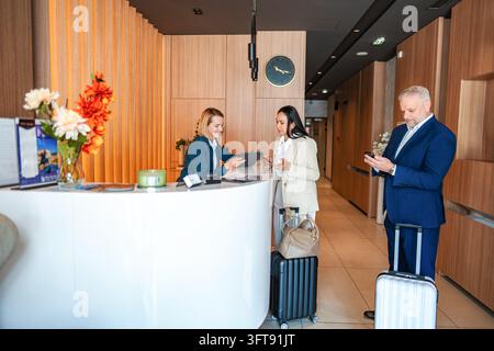 Clients s'enregistrant à la réception moderne de l'hôtel Banque D'Images