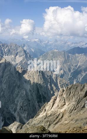 Une vue époustouflante met en valeur les pics escarpés et les vallées des Alpes de Lechtal. Des nuages blancs et duveteux dérivent au-dessus de la chaîne de montagnes, créant un paysage pittoresque Banque D'Images
