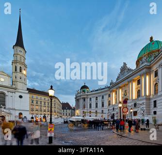 Les calèches Fiaker attendent devant le Michaelertrakt du palais impérial de la Hofburg au crépuscule dans le centre historique de Vienne, en Autriche. Banque D'Images