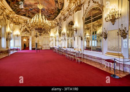 Salle d'apparat rococo avec fresques de plafond, lustres dorés, miroirs et tapis rouge dans l'ancienne résidence d'été impériale des Habsbourg. Banque D'Images