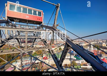 Gondole rouge du grand moulin à vent historique au-dessus du parc d'attractions du Prater à Leopoldstadt, avec les toits de la ville et un ciel bleu par une journée d'automne ensoleillée. Banque D'Images