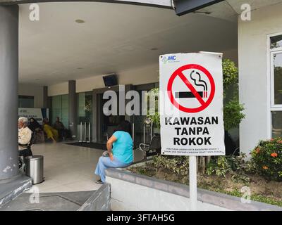 Balikpapan, Indonésie - 18 août 2026. Un panneau blanc « Kawasan Tanpa Rokok » (Zone non fumeuse) se dresse devant un bâtiment public moderne. Banque D'Images
