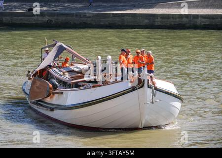 Des supporters néerlandais vêtus d'orange naviguent sur une péniche traditionnelle néerlandaise en bois le long de la Seine à Paris, France, le 5 août 2024, pendant les Jeux Olympiques de Paris 2024. Banque D'Images