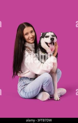 Possession d'animaux de compagnie et compagnie, jeune femme heureuse embrassant son chien husky sur un fond violet solide pour la publicité sur le style de vie et le bien-être animal Banque D'Images