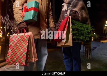 Couple se tenant la main et portant des cadeaux de Noël en plein air Banque D'Images