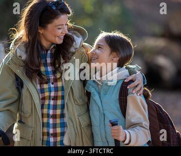 Mère et fille profitent d'une randonnée dans la nature. Elles sourient et se détendent ensemble tout en explorant l'extérieur pendant la saison automnale. Banque D'Images