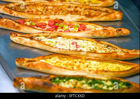 Pide turc traditionnel avec divers fromages, saucisses, viandes et garnitures de légumes, pains plats fraîchement cuits en forme de bateau avec une croûte dorée et croustillante Banque D'Images