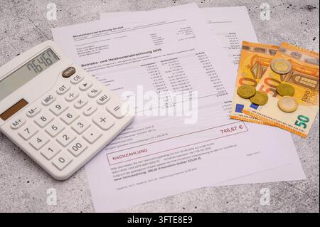 Calculatrice, billets et pièces en euros sur une facture de service et de frais de chauffage avec un arriéré de paiement de 746,67 euros. Image symbolique pour les frais de service en hausse Banque D'Images
