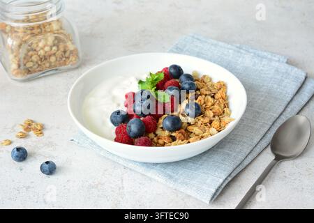 Bol de yaourt avec des baies, des framboises et des myrtilles, et du granola sur la table avec une serviette Banque D'Images