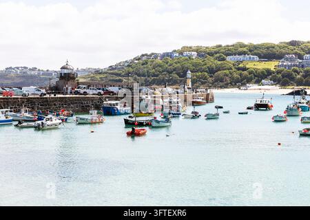 St Ives, Cornouailles, Royaume-Uni. Bateaux de pêche traditionnels et bateaux de loisirs amarrés dans les eaux calmes du port de St Ives avec la digue du port, phare Banque D'Images