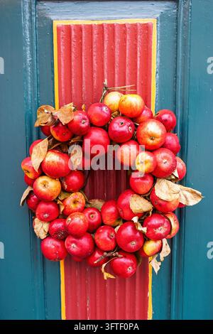 Couronne décorative de pommes rouges sur une porte en bois colorée Banque D'Images