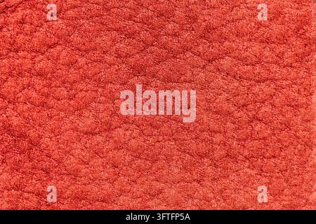 Gros plan d'une texture de daim rouge riche présentant un velours doux et un motif de grain fin, offrant une esthétique chaude et tactile.  Banque D'Images