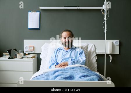 Portrait d'un homme d'âge moyen souriant reposant dans un lit d'hôpital Banque D'Images